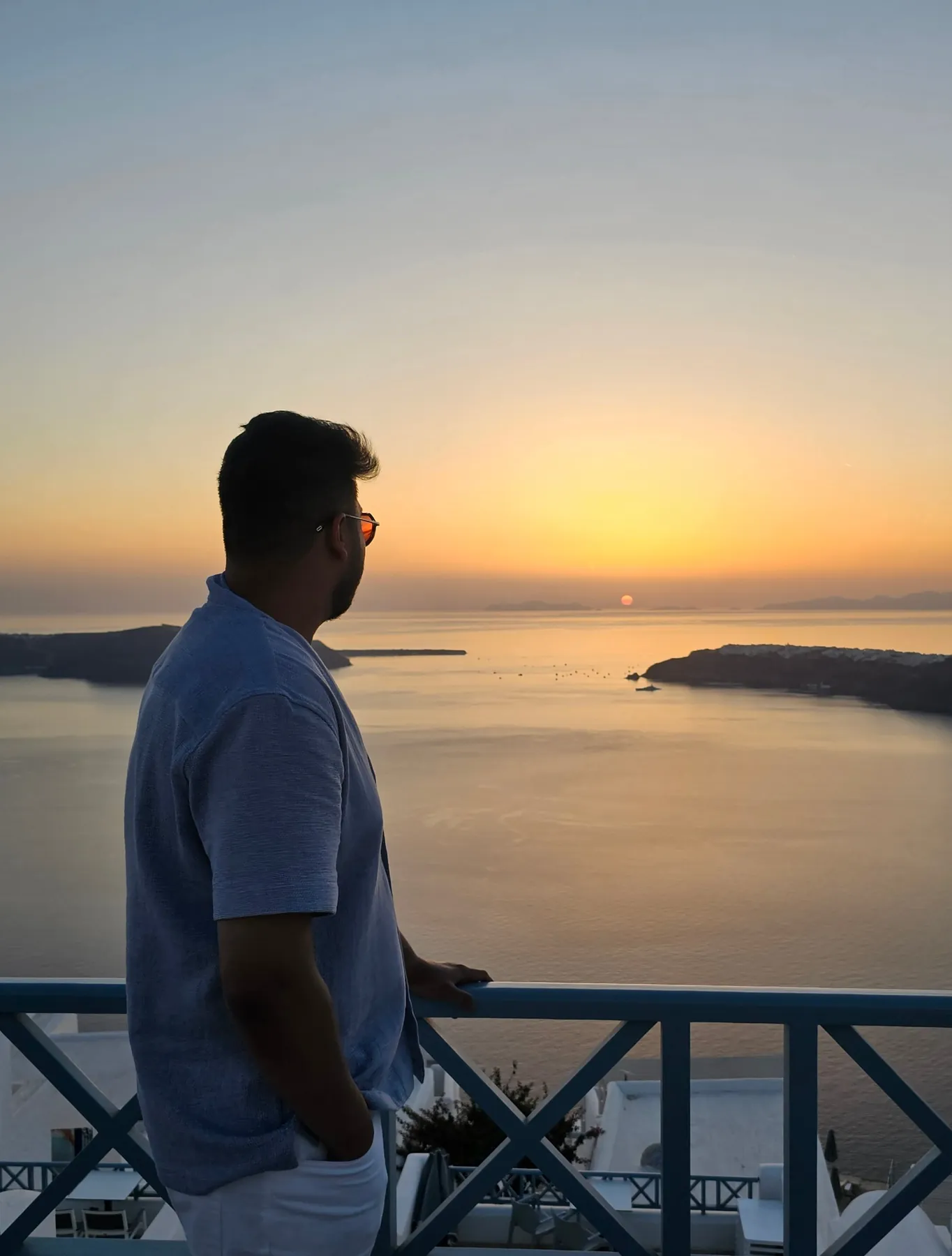 Sandeep in silhouette on the balcony of his room, watching the sun set over the Santorini caldera
