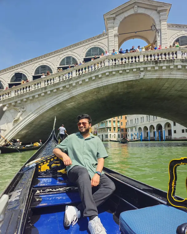 Sandeep sitting in a gondola under the Rialto Bridge in Venice